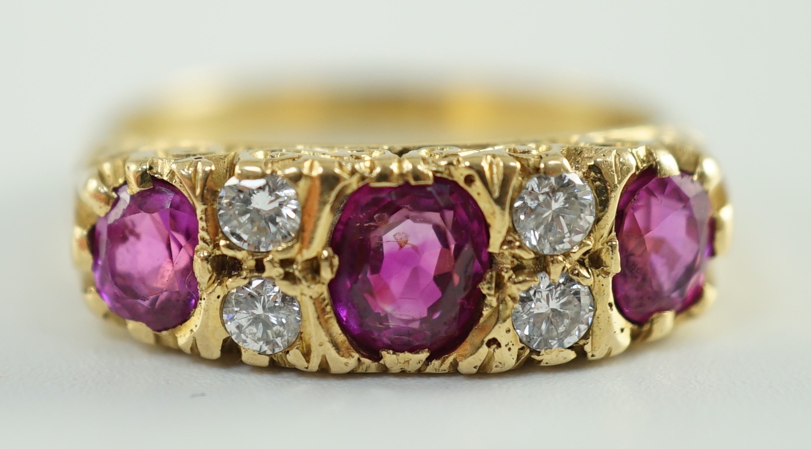 An early to mid 20th century 18ct gold, single stone oval cut ruby, two stone pink sapphire and four stone round cut diamond set half hoop ring